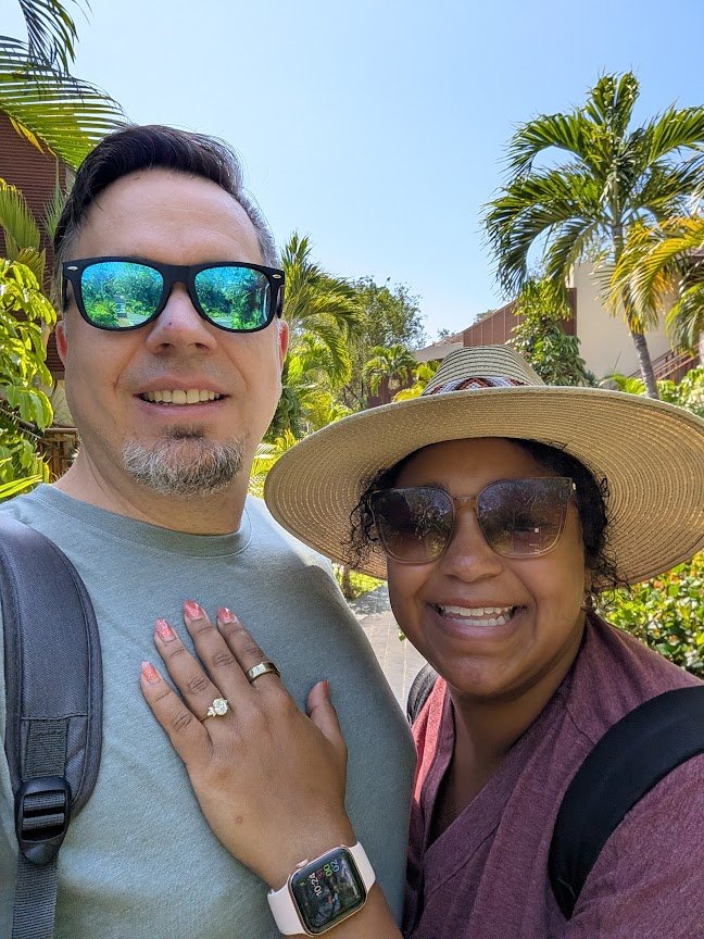 Jennifer and Joe smiling together in the resort gardens, Jennifer's hand resting on Joe's chest